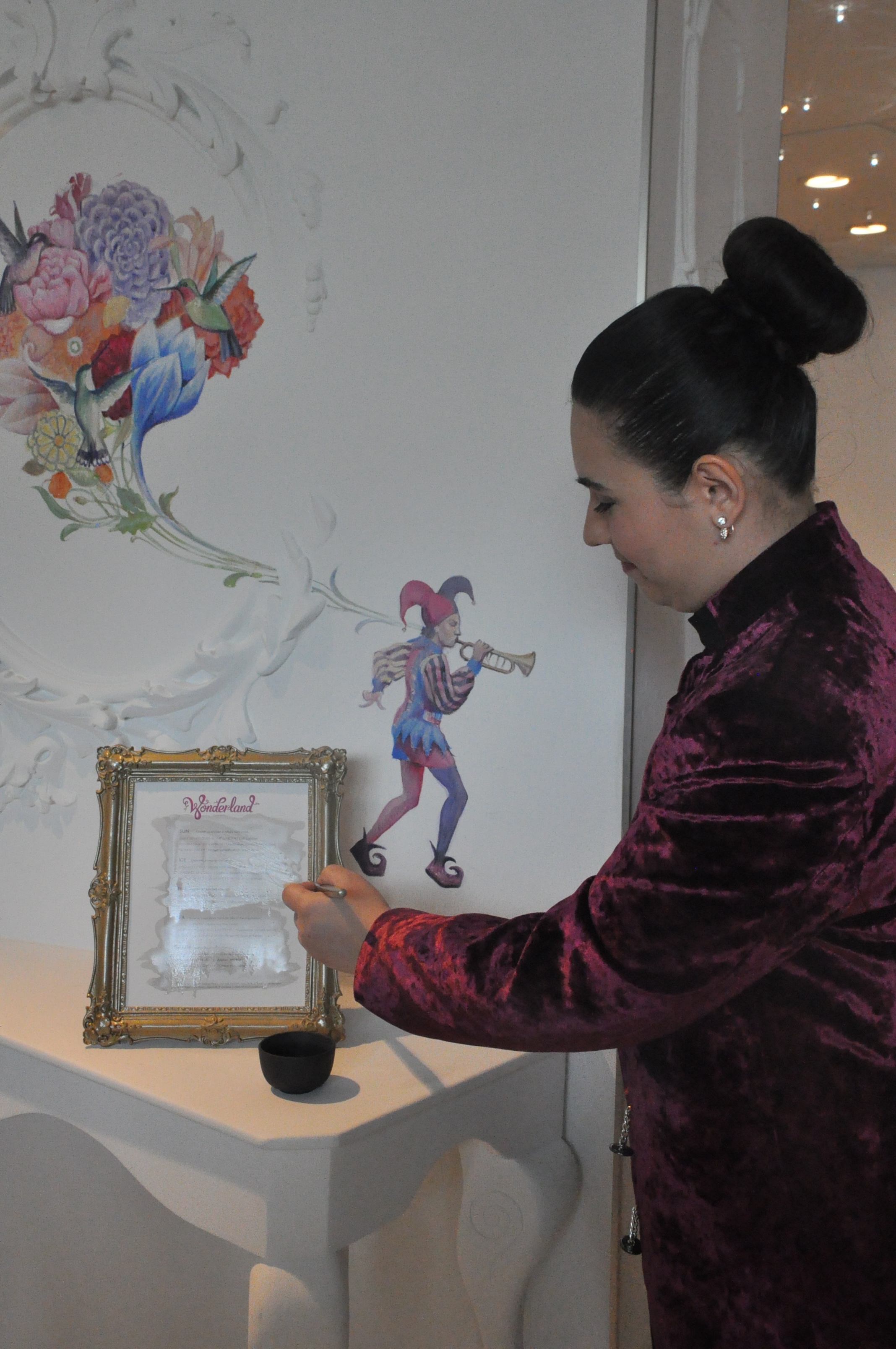 A brasileira Bárbara Uchiyama, que trabalha no Wonderland, pintando o cardápio para que o menu se torne visível