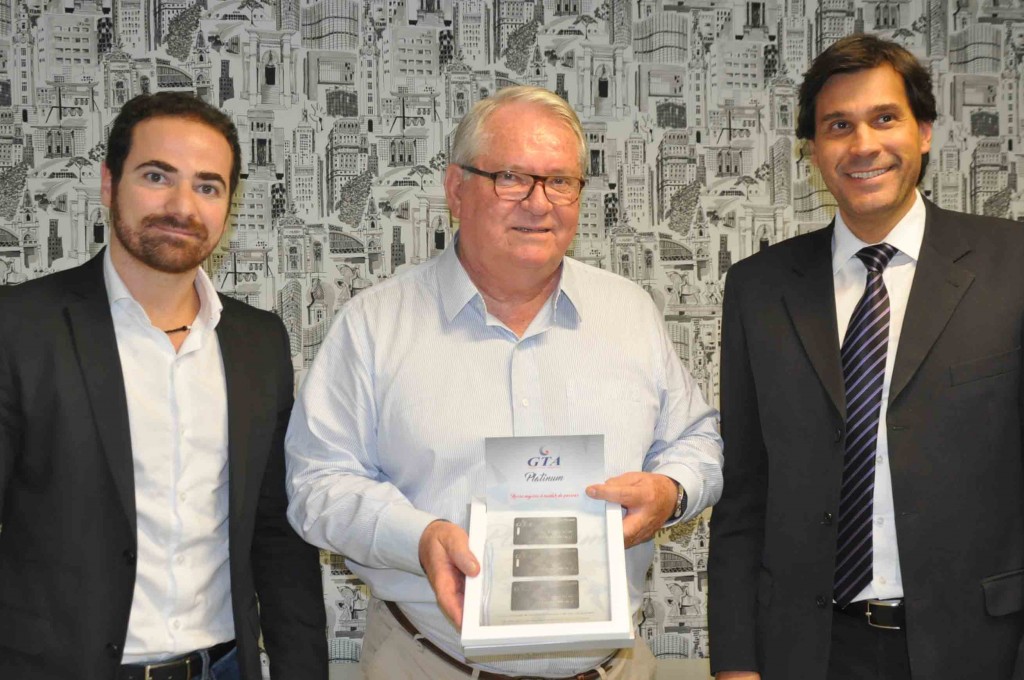 Gustavo Monteiro e Rogério Esteves, da GTA entregam cartão Platinum Member à Roy Taylor, do M&E