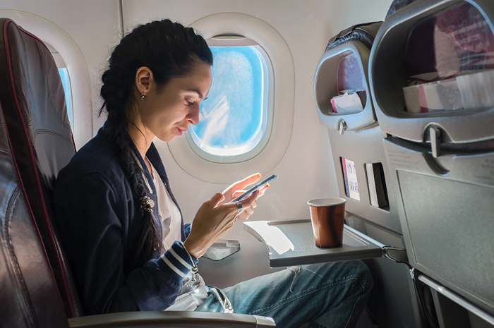 Maioria dos brasileiros revela que se desconectar nas férias provoca mais estresse e ansiedade 1 Woman sitting on plane with mobile phone shutterstock 312677084 1 Maioria dos brasileiros revela que se desconectar nas férias provoca mais estresse e ansiedade