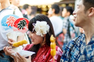 Japanese couple dating at Matsuri, wearing yukata, eating dango