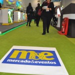 Logo do M&E, media partner do evento, na área das Américas