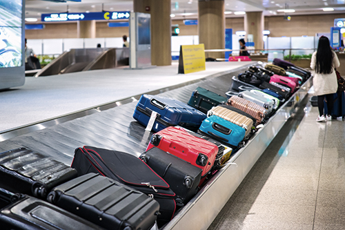 Traveler waiting for a travel bag on the belt in airport after arrival to airport destination flight