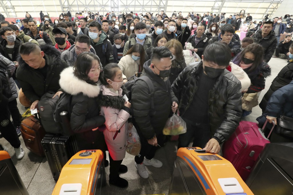 Travelers wear face masks as they line up at turnstiles at a train station in Nantong, eastern China's Jiangsu province, Wednesday, Jan. 22, 2020. The number of cases of a new virus has risen to over 400 in China and the death toll to 9, Chinese health authorities said Wednesday. (Chinatopix via AP)