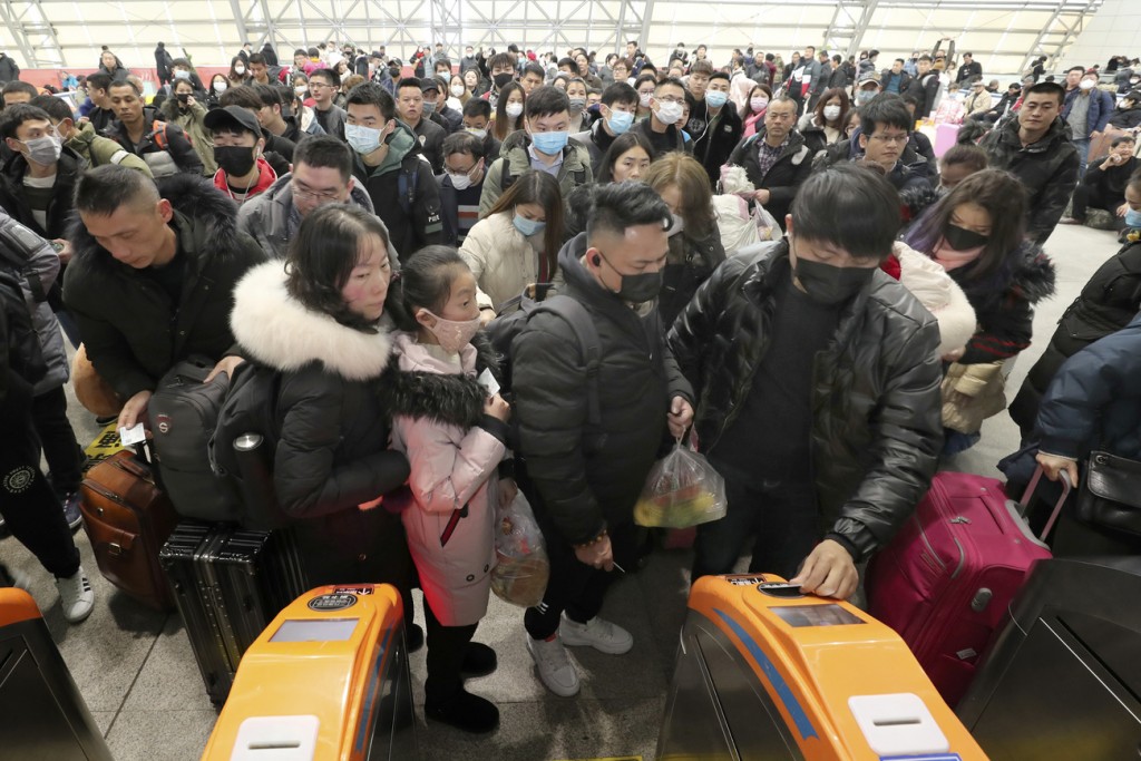 Coronavírus: China suspende viagens em grupo e venda de pacotes 1 Travelers wear face masks as they line up at turnstiles at a train station in Nantong, eastern China's Jiangsu province, Wednesday, Jan. 22, 2020. The number of cases of a new virus has risen to over 400 in China and the death toll to 9, Chinese health authorities said Wednesday. (Chinatopix via AP)