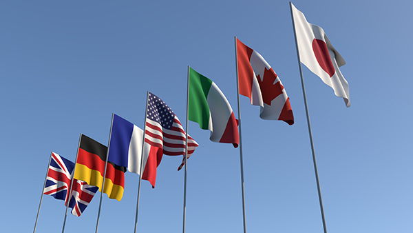 Seven flags of the Group of Seven are developing against the blue sky. G7