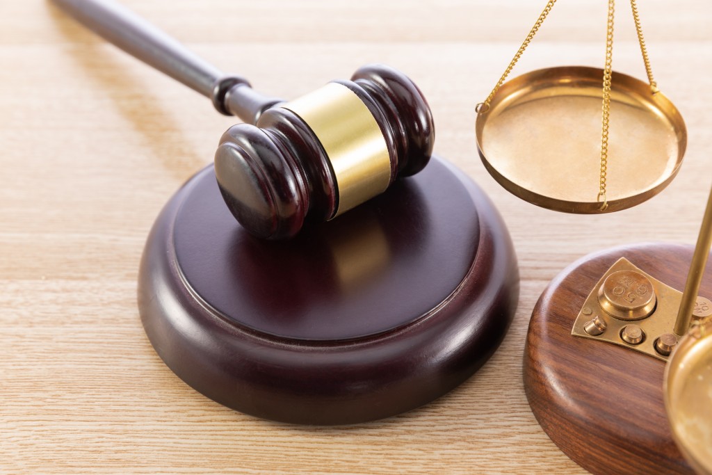 A high angle shot of a gavel and a scale on a wooden surface