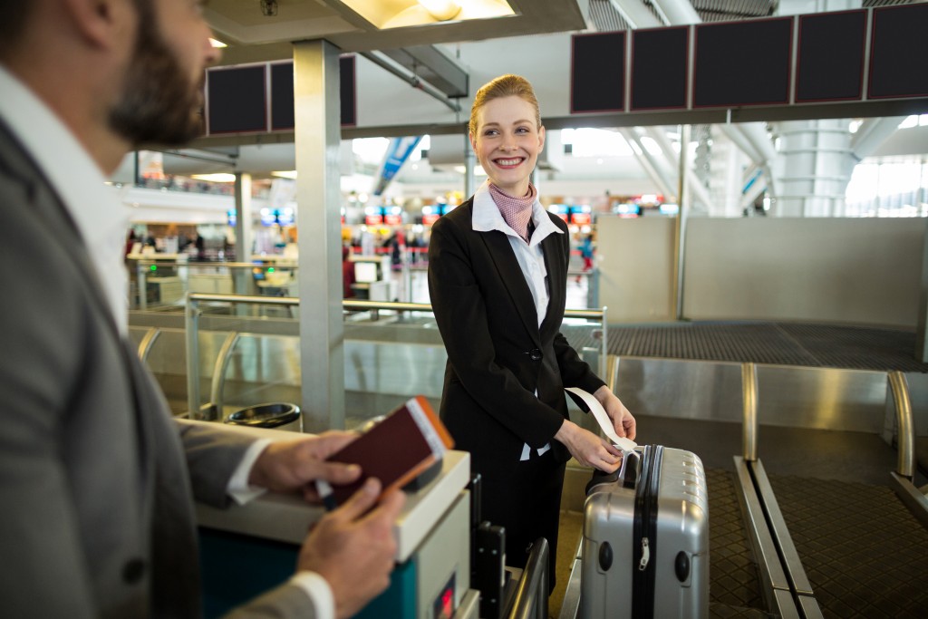 Airline check-in attendant sticking tag to the luggage of commuter at airport