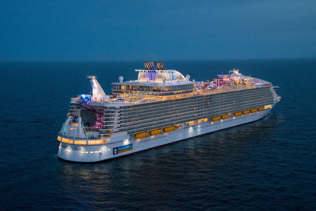 Royal Caribbean para de aceitar novas reservas para cruzeiros no início de janeiro SY, Symphony of the Seas, Aerial view at night offshore Barcelona, Spain, on April 5, 2018, dusk, evening, starboard aft view, horizon, ship lights,