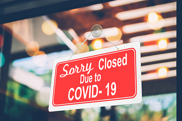 A sign reading "Sorry, closed due to Covid-19" on the glass door of the cafe
