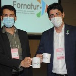 Fabrícia Amaral e Bruno Wendling com as canecas mostrando a nova marca do Fornatur