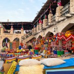 Banca de almofadas, mantas, tapetes e outros tecidos colorindo a rua principal de Souq Waqif em Doha
