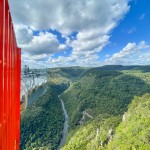 Vista do Skyglass Canela para o vale, com cachoeira rio e montanhas emoldurando a paisagem