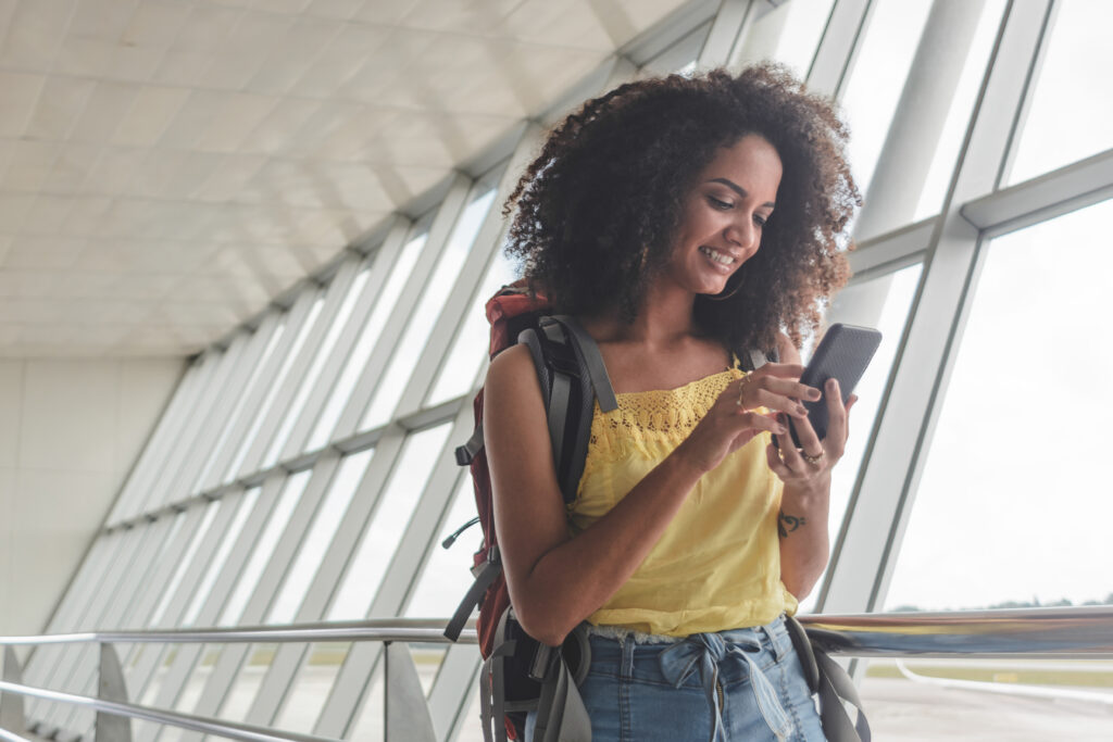 young woman backpack checking boarding schedule highresolution Verificação de identidade digital chega ao Aeroporto Internacional de Aruba