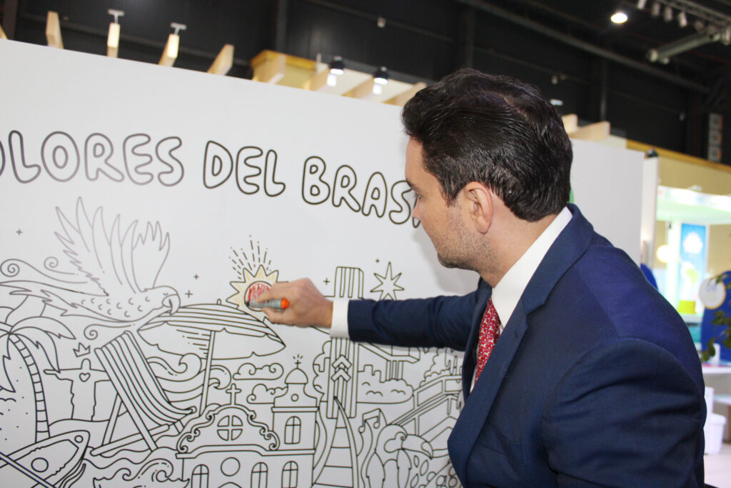 Celso Sabino, ministro do Turismo, pinta o mural no estande da Embratur