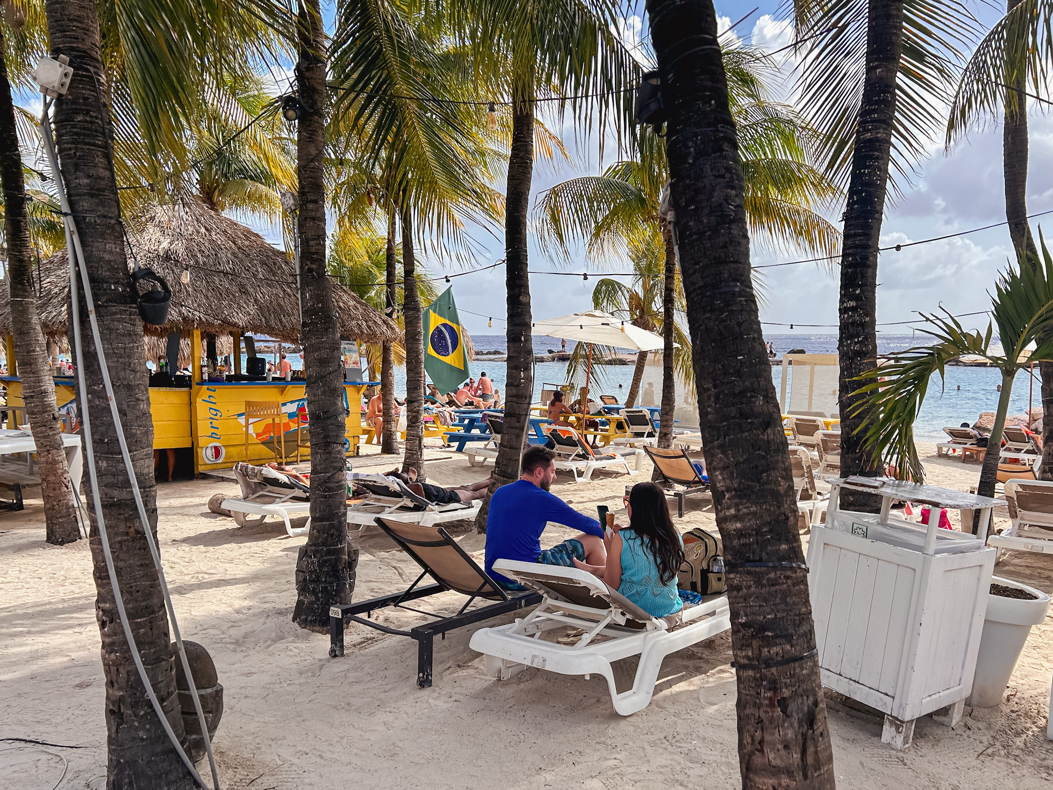 Na areia, os turistas ouvem música e aproveitam o mal calmo Na areia, os turistas ouvem música e aproveitam o mal calmo