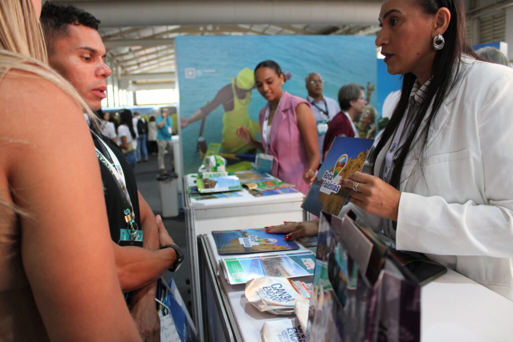 Marta, da Trip da Areia, apresentando o destino para Gleydson, da Check-In Free, e Maria Cristina de Paulo Araújo