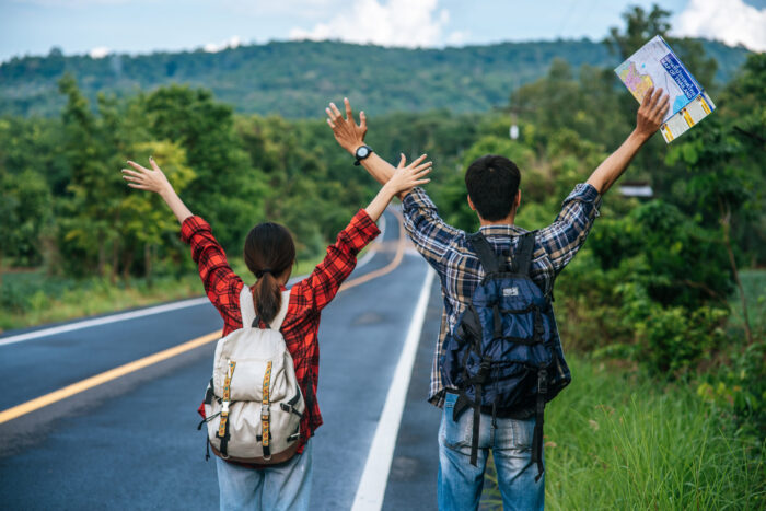 Mulheres preferem paisagens, homens preferem aventura: estudo revela preferências e destinos dos sonhos dos viajantes 1 both male female tourists carry backpack stand road raise their hands both sides scaled e1726489444279 Mulheres preferem paisagens, homens preferem aventura: estudo revela preferências e destinos dos sonhos dos viajantes