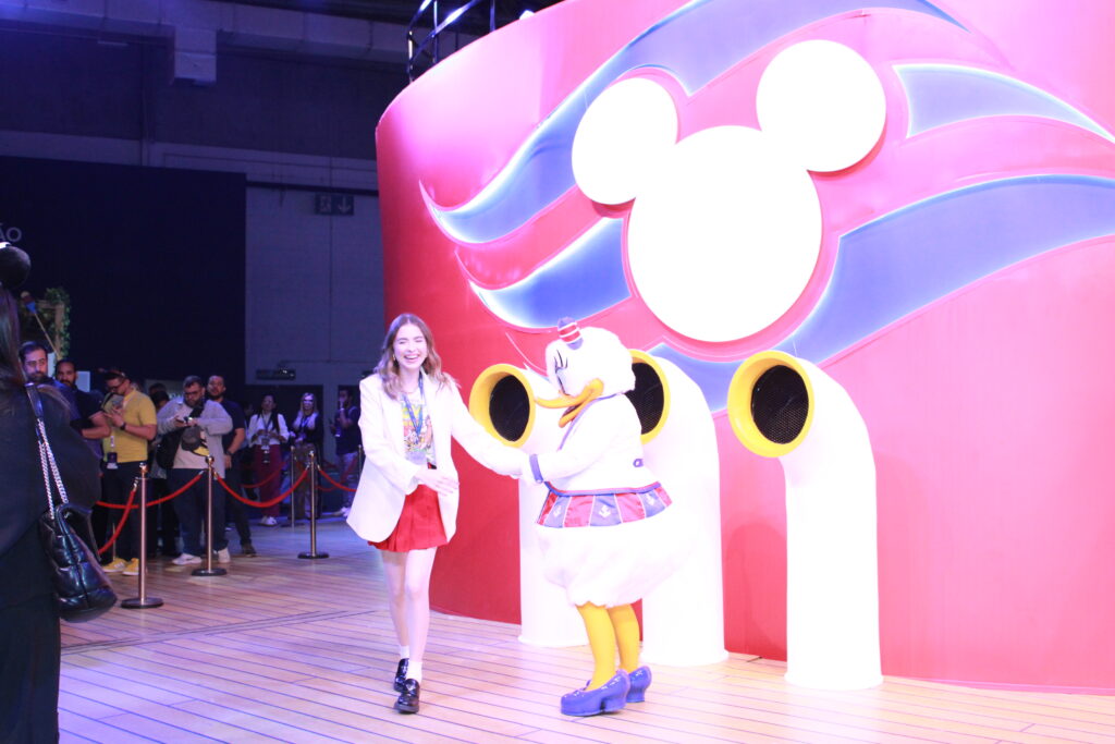 Influenciadora Fernanda Tumas no estande da Disney Cruise Line, junto da personagem margarida