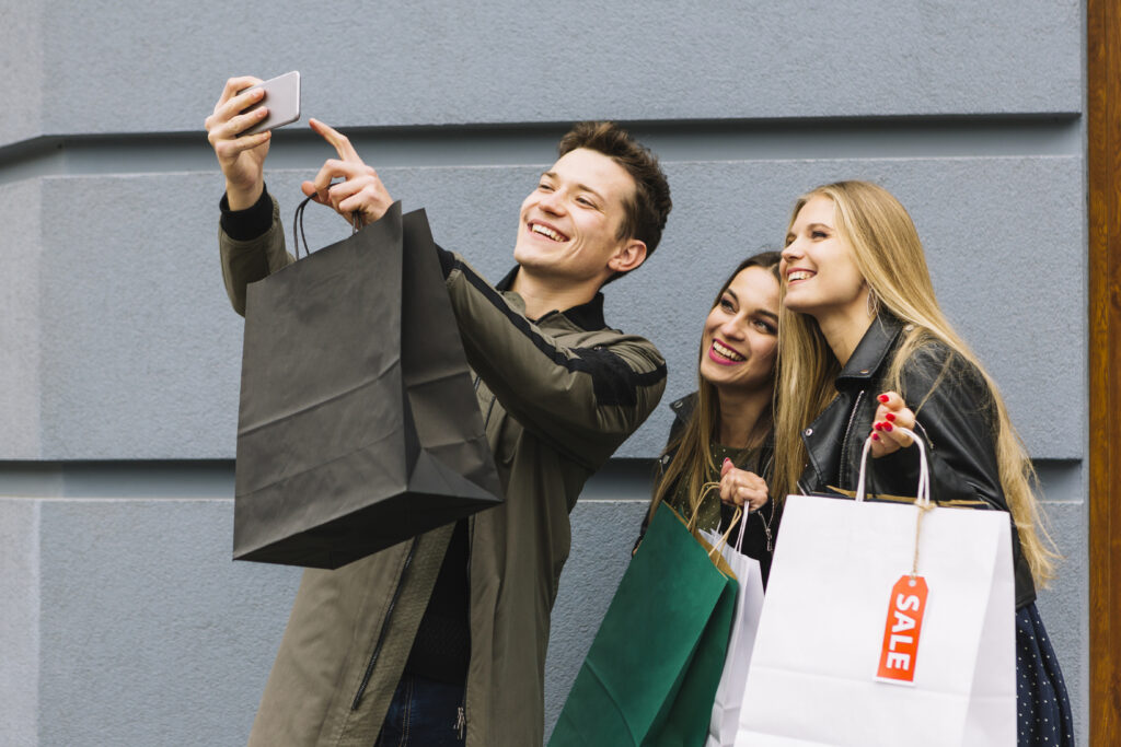 smiling man taking selfie with his female friend holding shopping bags Alerj vota hoje (26) o Tax Free: entenda impactos e como funcionará aplicação na prática