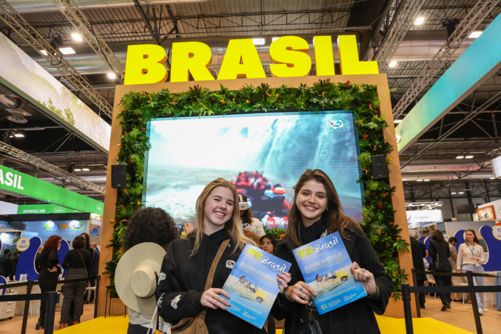 Participantes da feira posam com a revista especial de 2025