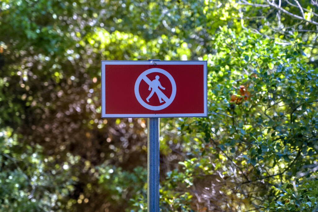 red no walking sign people forest Descubra locais proibidos ou restritos de visitar pelo mundo; Brasil está na lista