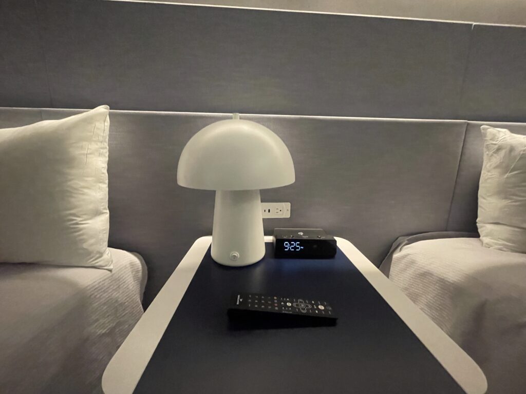 Relógio com alarme, tomadas e luminária entre as camas