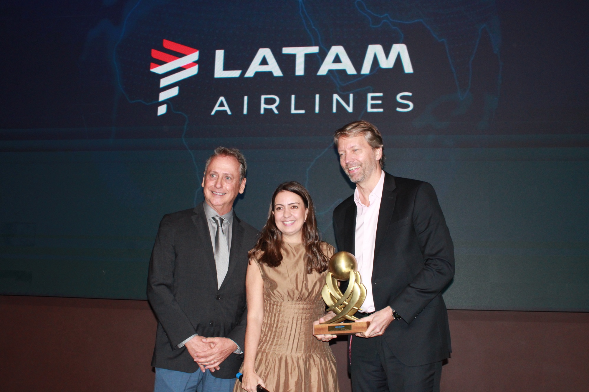 Jerome Cadier e Aline Mafra, da Latam, recebem o prêmio de 'Melhor Companhia Aérea Internacional para Europa e África' das mãos de Luís Vabo, do Reserve (Giulia Jardim/M&E)