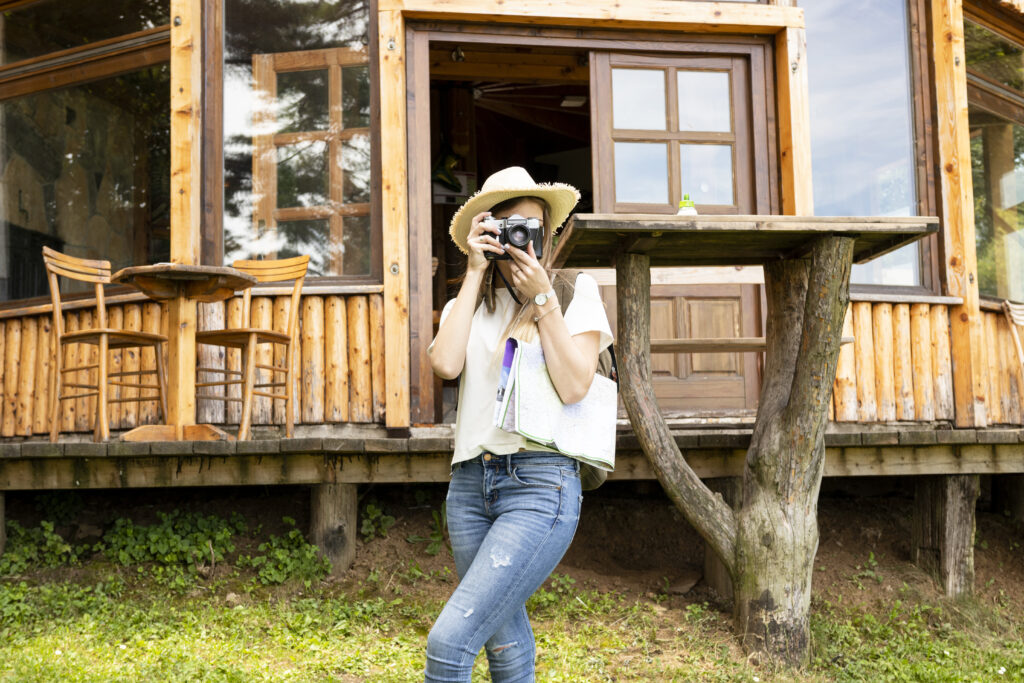 Receita Federal e novo Código Civil: alugar imóveis pelo Airbnb deve se tornar mais difícil 1 woman taking picture front house Receita Federal e novo Código Civil: alugar imóveis pelo Airbnb deve se tornar mais difícil