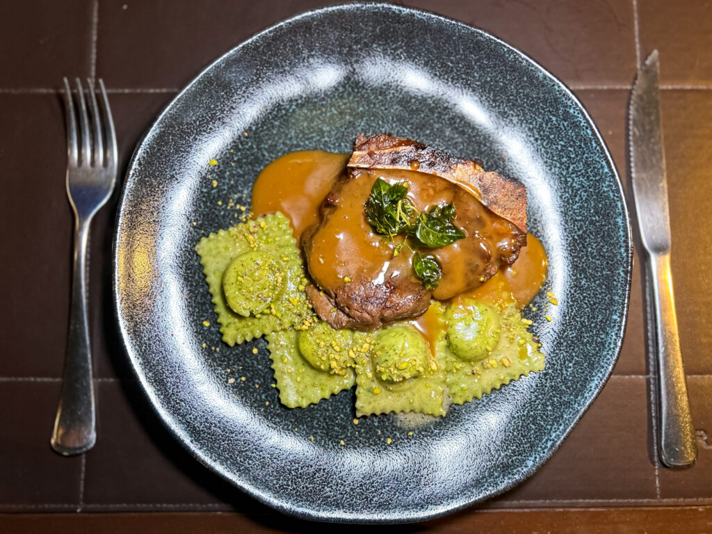 Medalhão de filet mignon assado no braseiro ao molho roti. Acompanha ravioli de espinafre e damasco