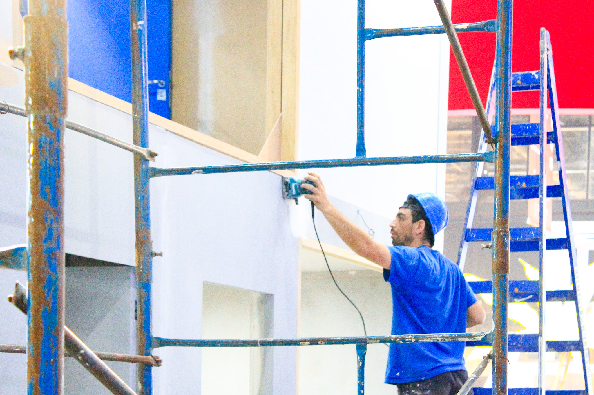 Um trabalhador aplicando gesso para revestir e finalizar o estande