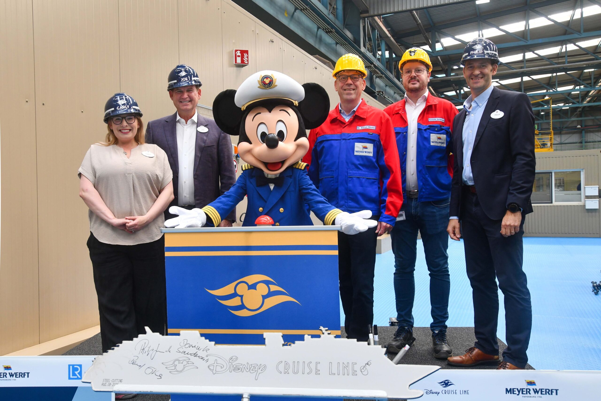 Joe Schott, Philip Gennotte, Bernd Eikens e Carly Scott participam do corte do primeiro pedaço de aço do Disney Believe, em agosto de 2025, no estaleiro Meyer Werft, na Alemanha